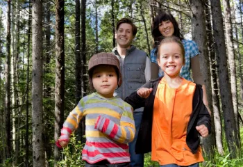 Two children and two parents walking through a forest