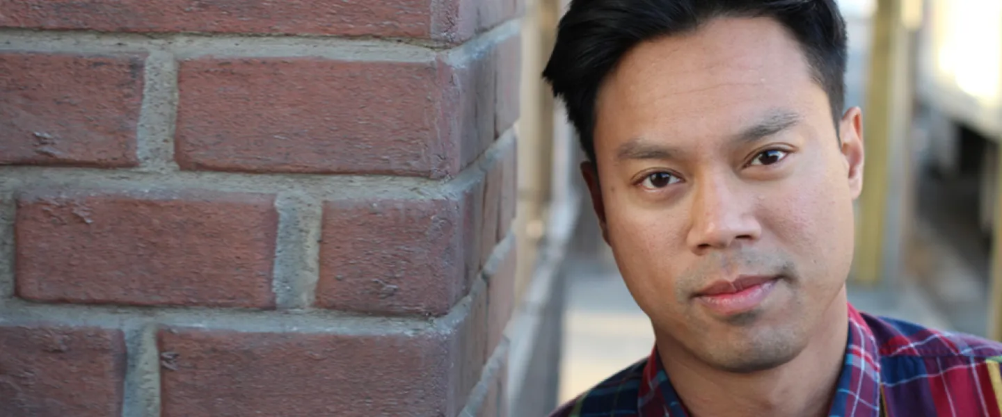 A man leans against a brick wall.