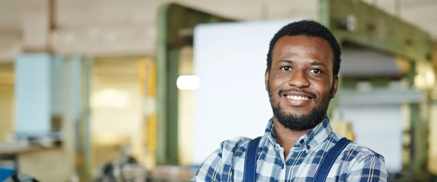 A smiling man with his arms crossed stands in front of machinery.