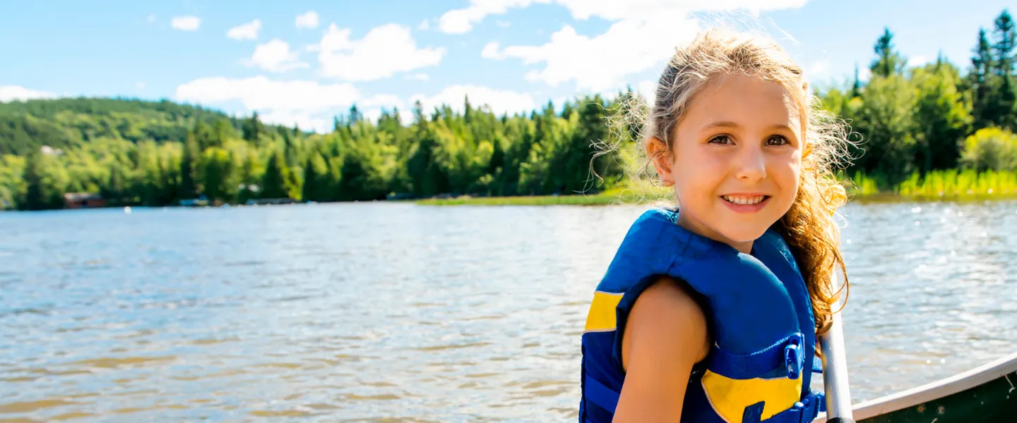 A girl wearing a lifejacket sits at the front of a canoe.