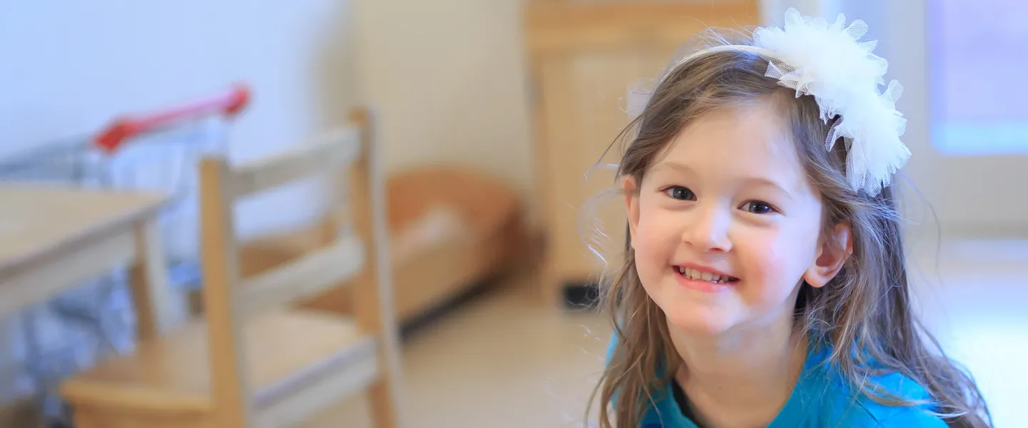 A smiling girl with a bow in her hair.