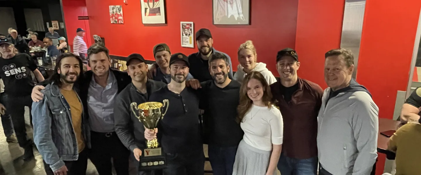 Group photo of winning team holding a large trophy at the post-tournament celebration