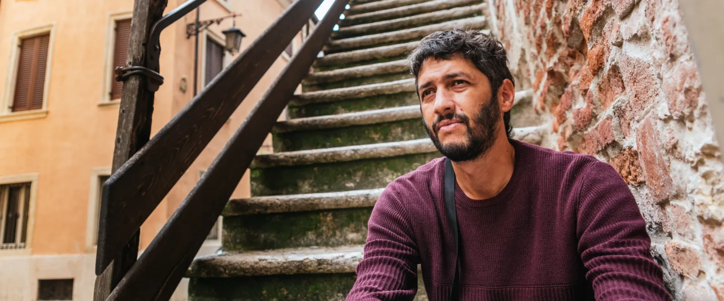 Man sits outside on a staircase.