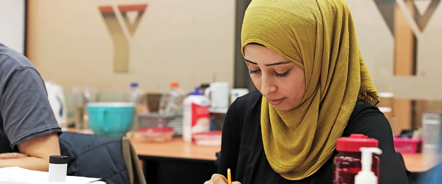 Woman sits at a classroom desk working.