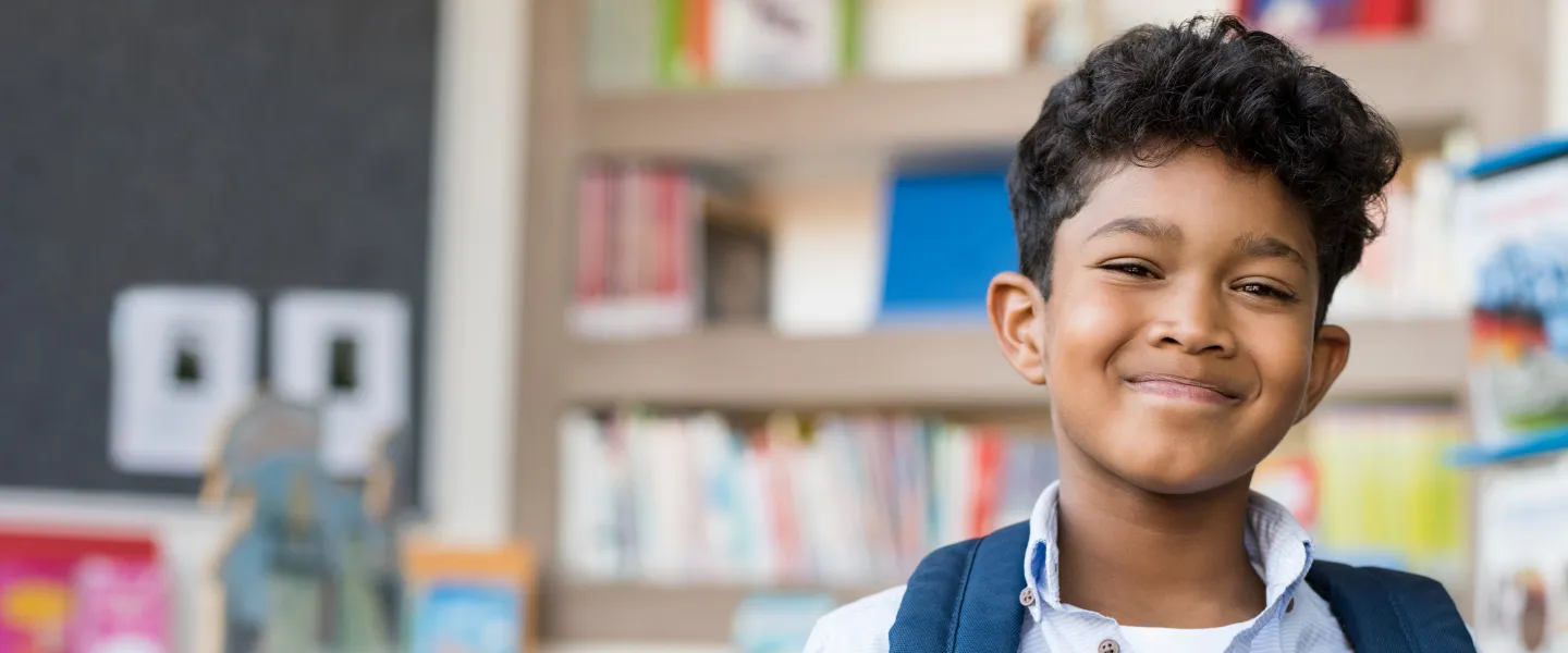 A young boy smiles in a library.