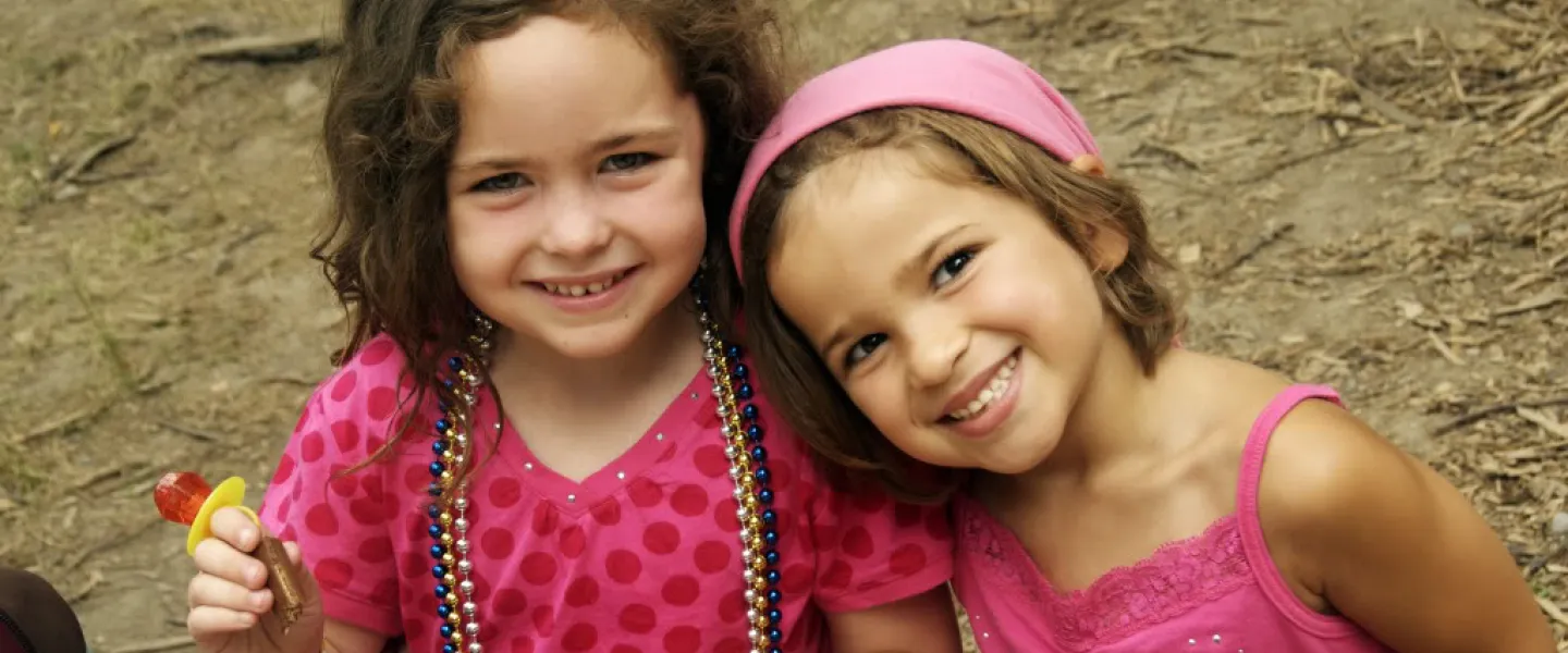 Two smiling young girls both wearing pink.