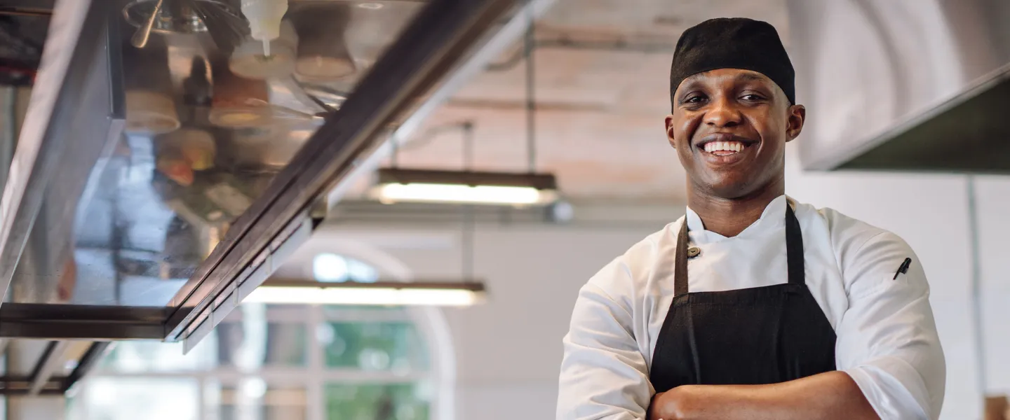 A chef smiling with his arms crossed