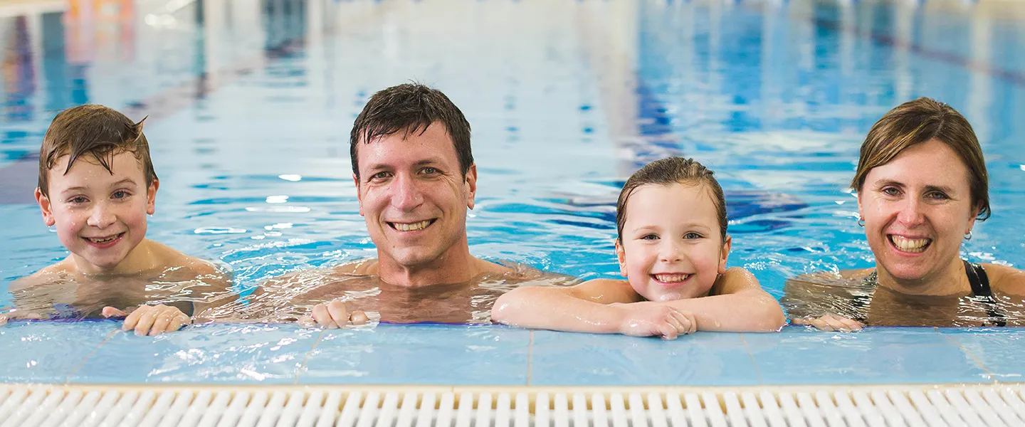 A family of four at the edge of a swimming pool