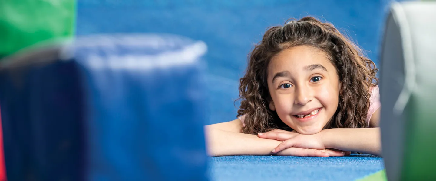 A young girl poses in a soft play area.