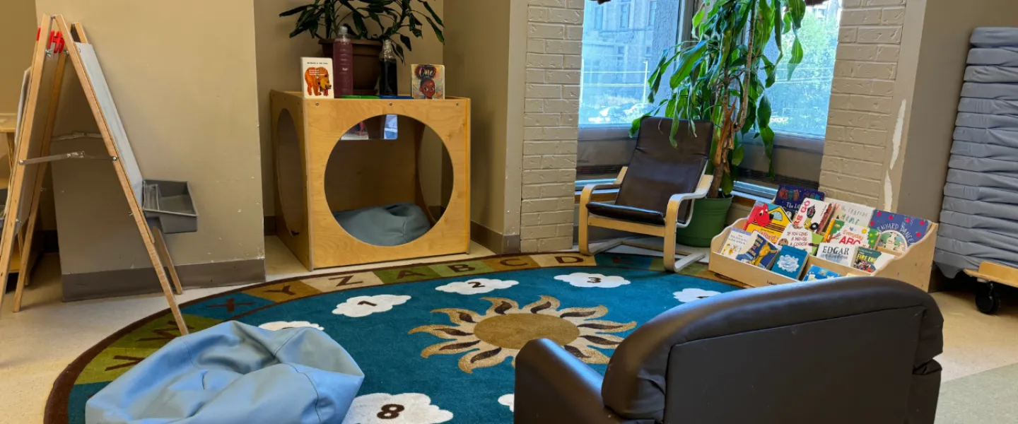 A rug and seating area with books and an easel at the Taggart Child Care Centre