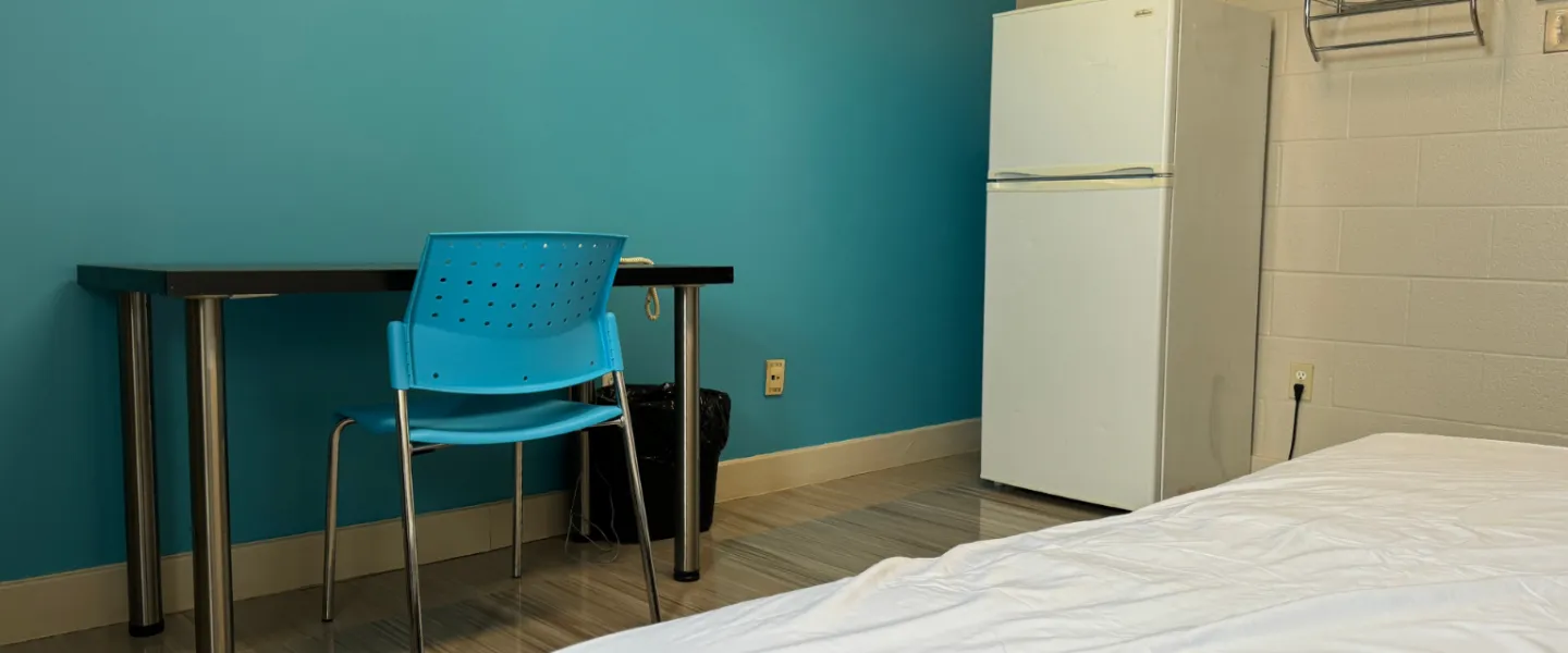 Second Stage Housing bedroom with a single bed, desk and chair, and fridge