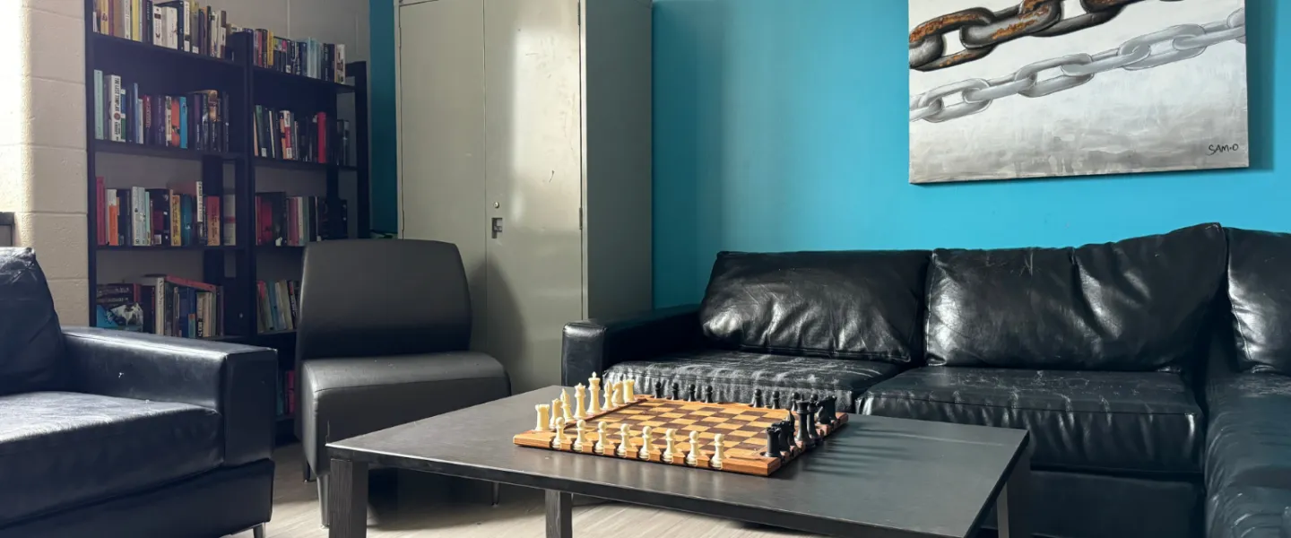 Second Stage Housing lounge with couches, artwork, a bookshelf, and a chess board