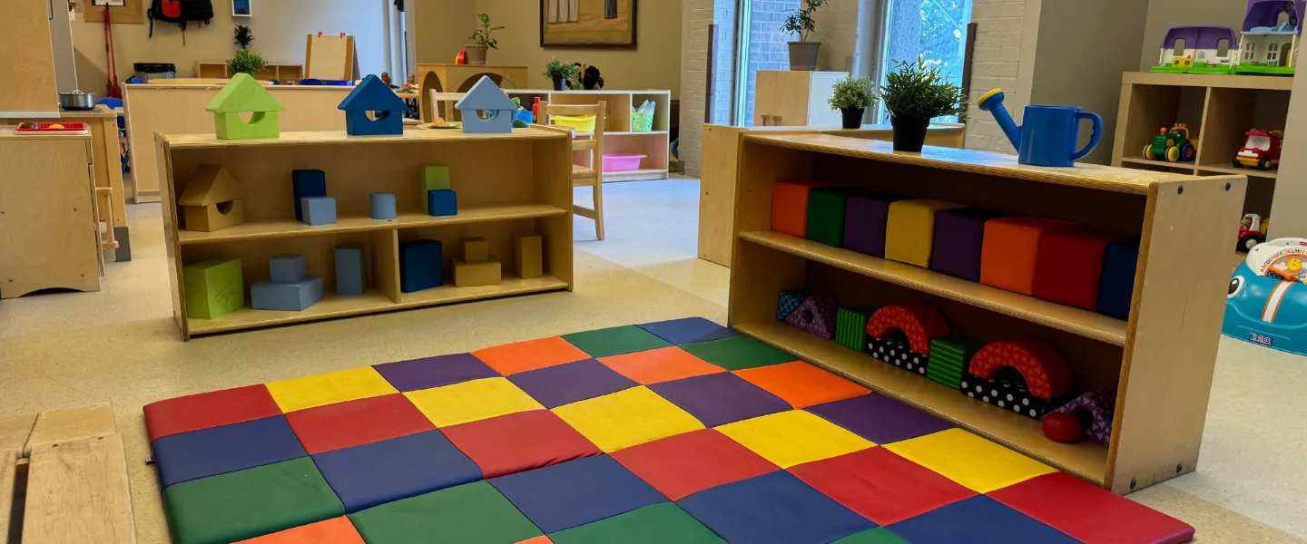 A room with colourful geometric toys and a colourful rug at the Taggart Child Care Centre.