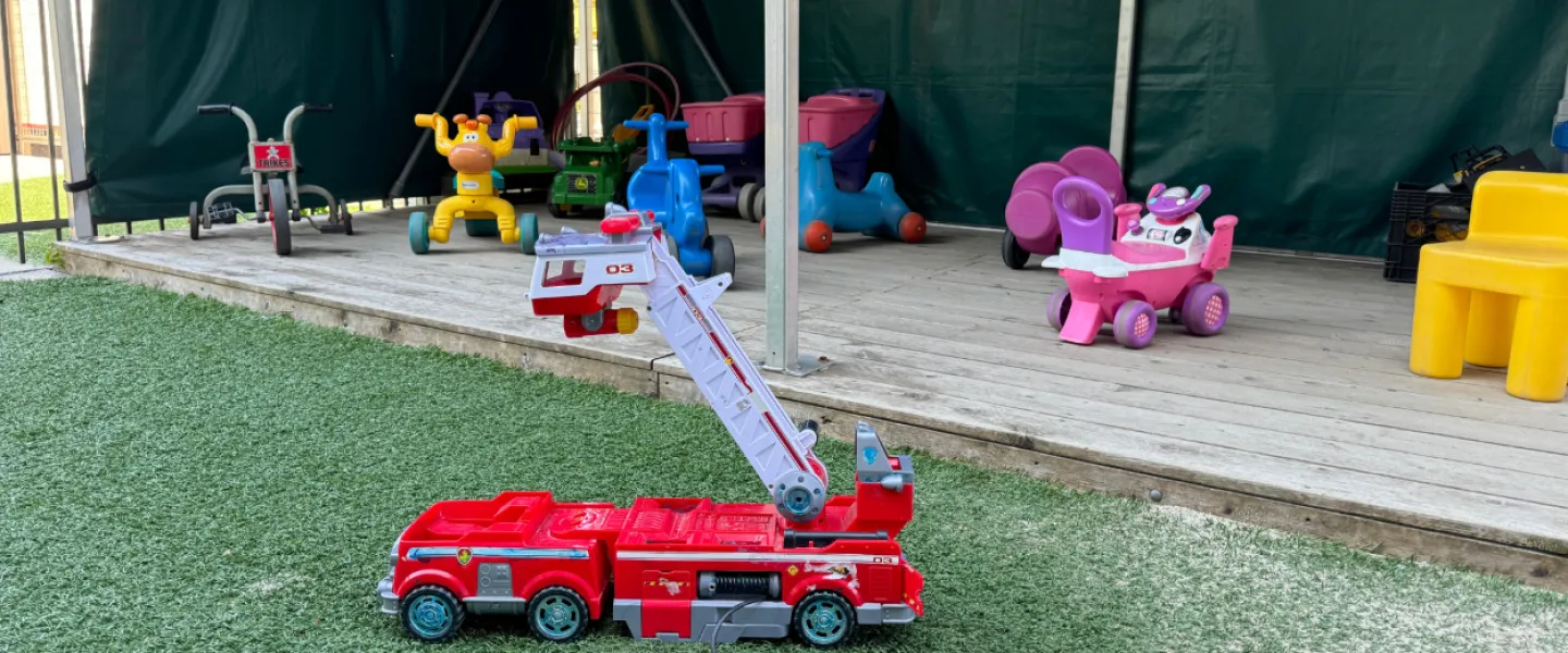 An outdoor play area with toy trucks and bikes.