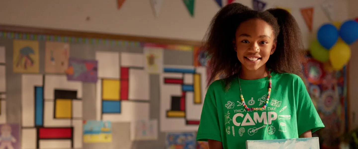 A girl in a green Camp t-shirt holding a painting