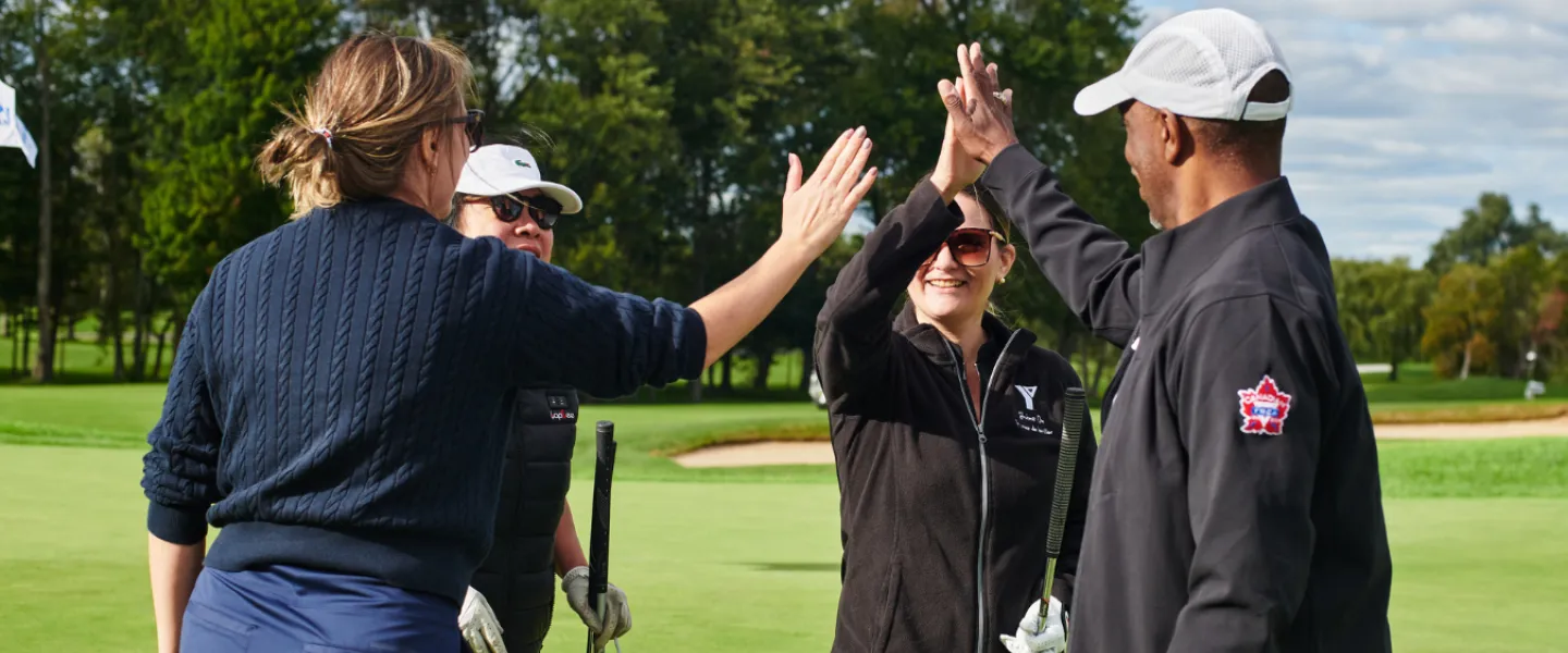 A team of four golfers high fiving on a course