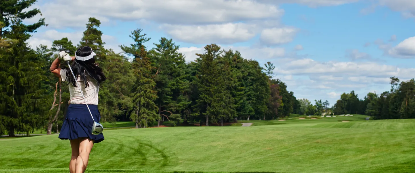 A golfer swinging her club on a course