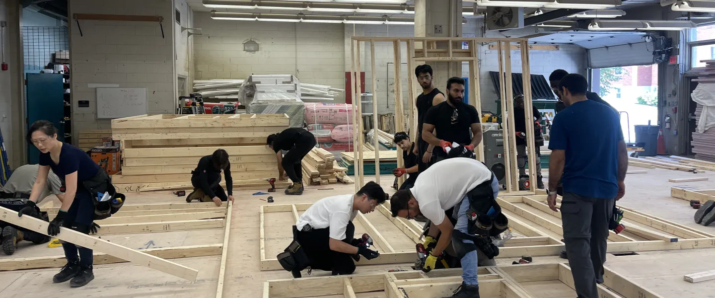 Skilled trades training program participants in a workshop, drilling into wooden planks