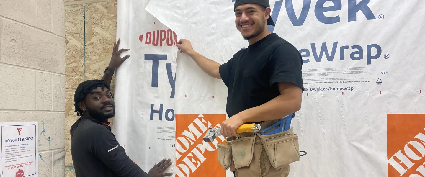 Two skilled trades program participants in a workshop, smiling at the camera