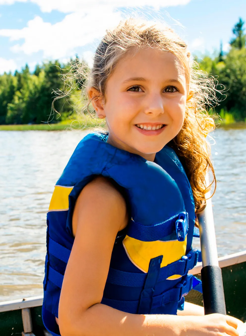 A girl wearing a lifejacket sits at the front of a canoe.