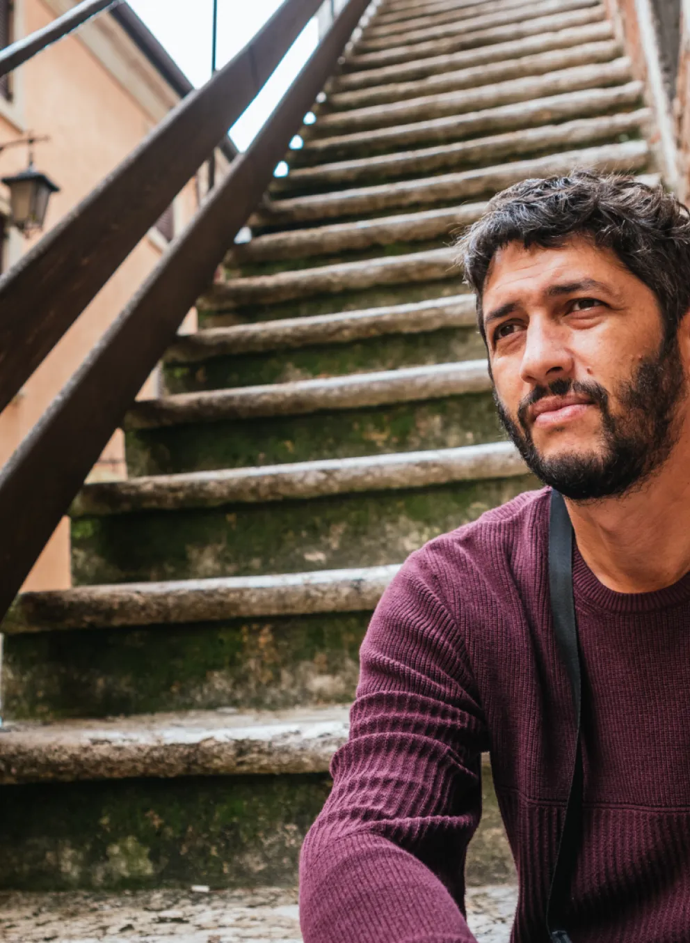 Man sits outside on a staircase.