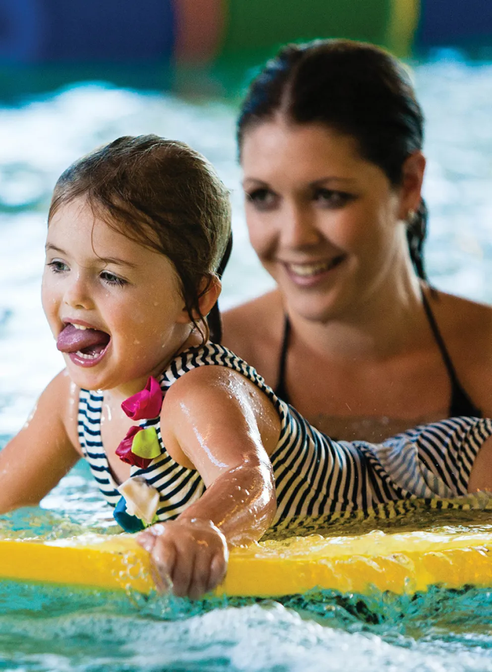 A mother and her daughter swimming in the pool.