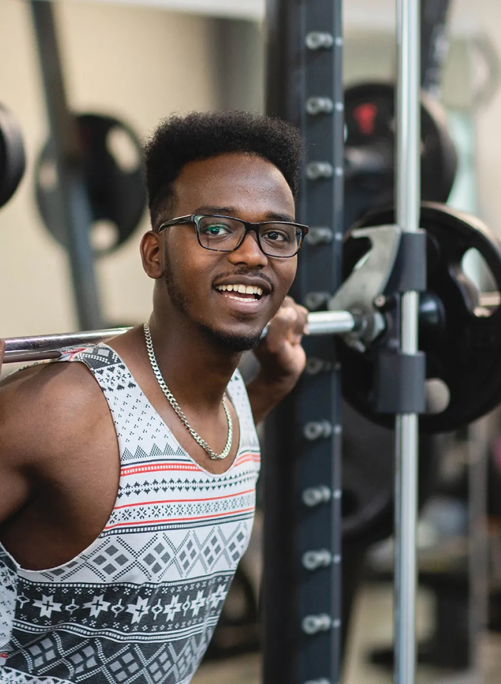 A young man holding up a barbell over his shoulder