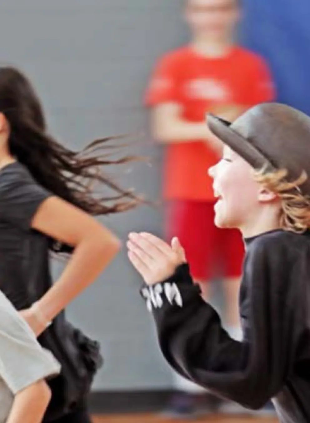 A group of children run in a gymnasium.