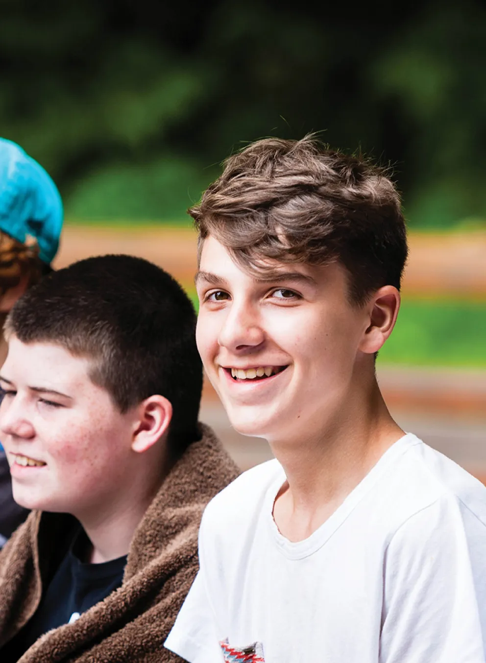 A group of teenage boys sit together in an outdoor setting.