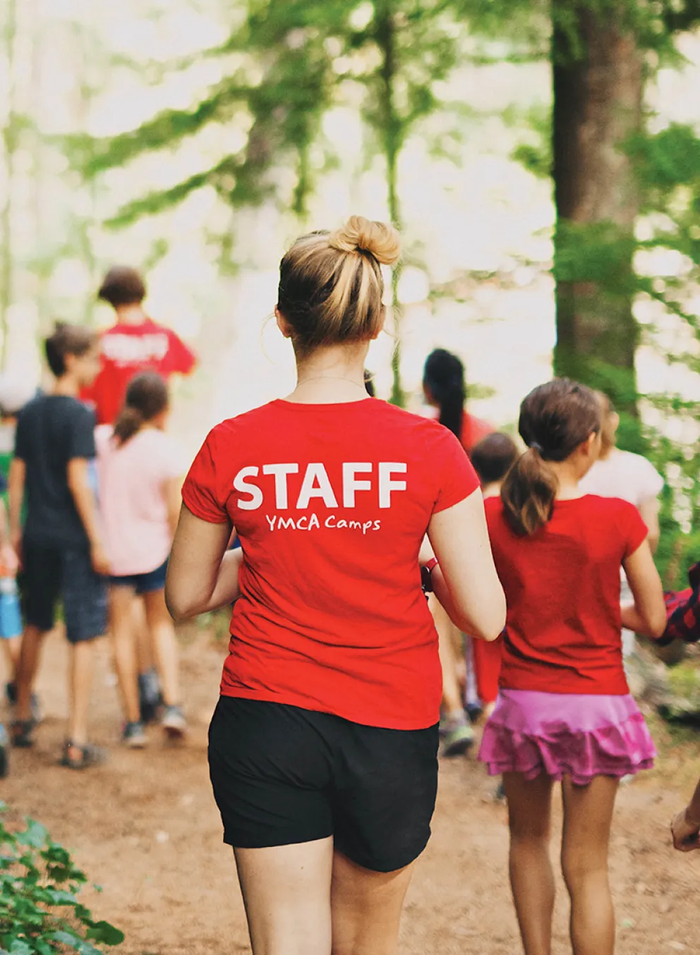 A group of children and camp counsellors walking down an outdoor path