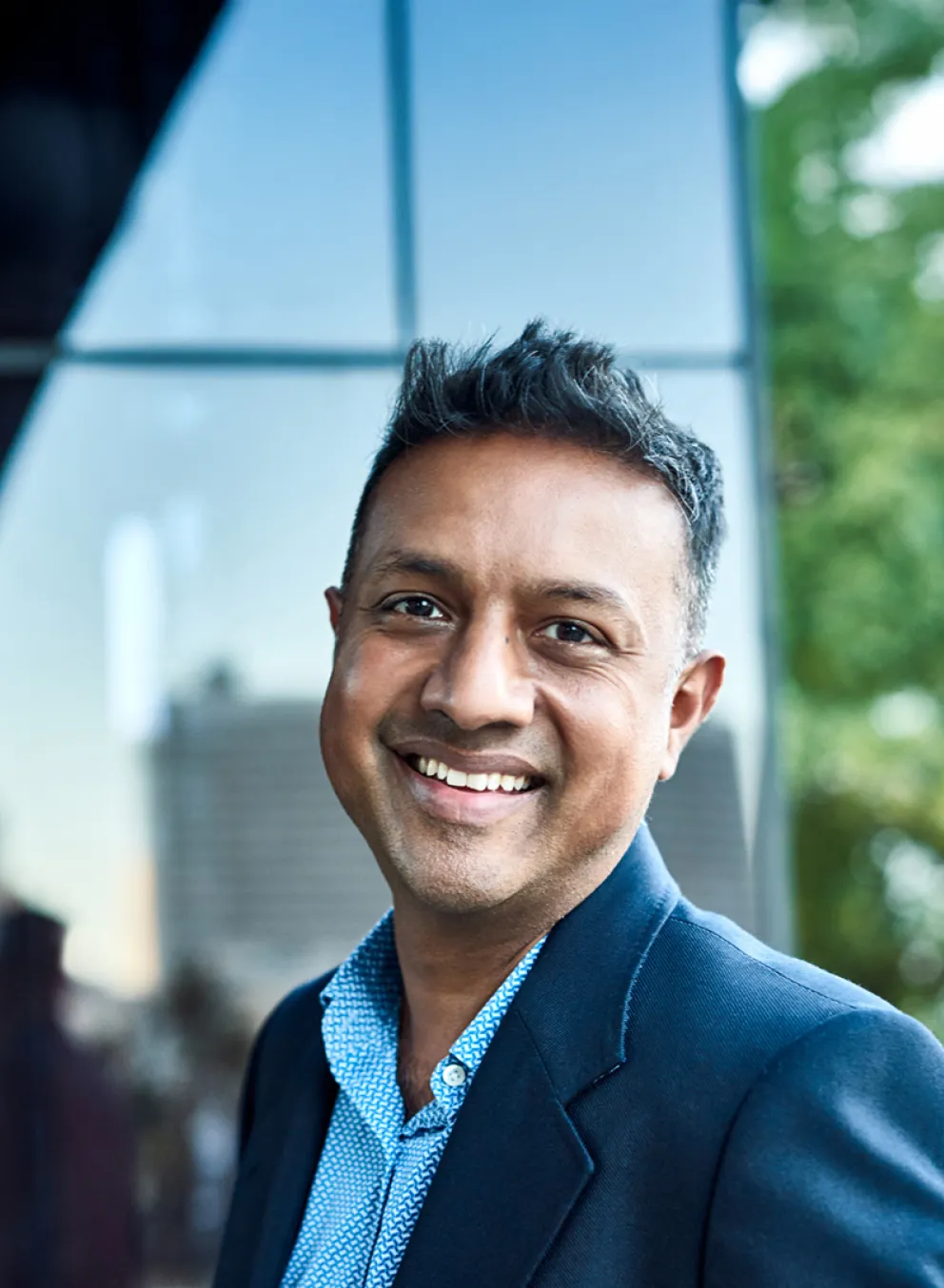 A smiling man stands outside the entrance to an office building.