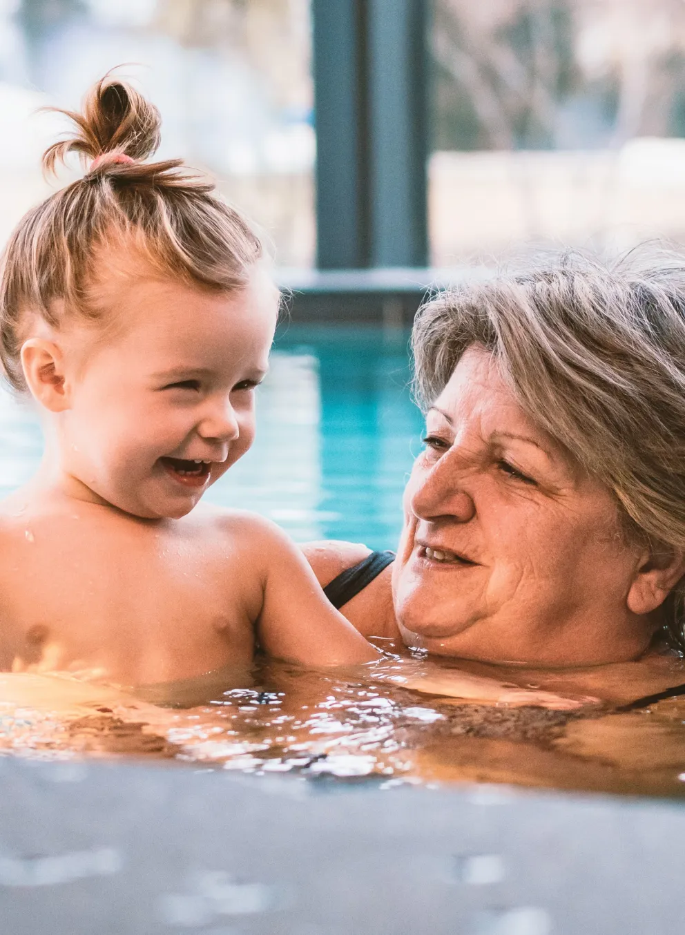 Three generations of family members play together in an indoor swimming pool
