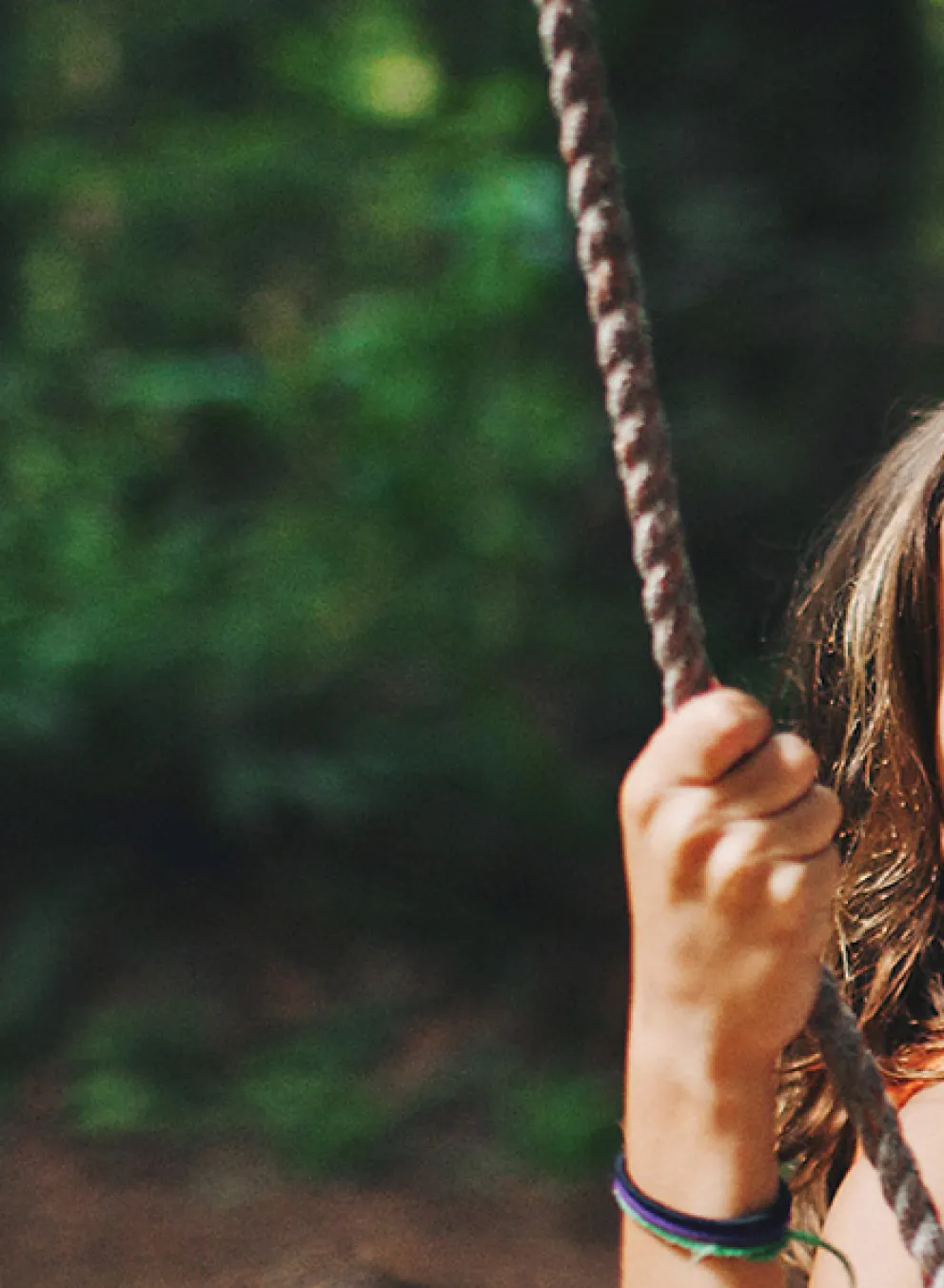 A young girl beams with happiness as she swings back and forth on a swing.