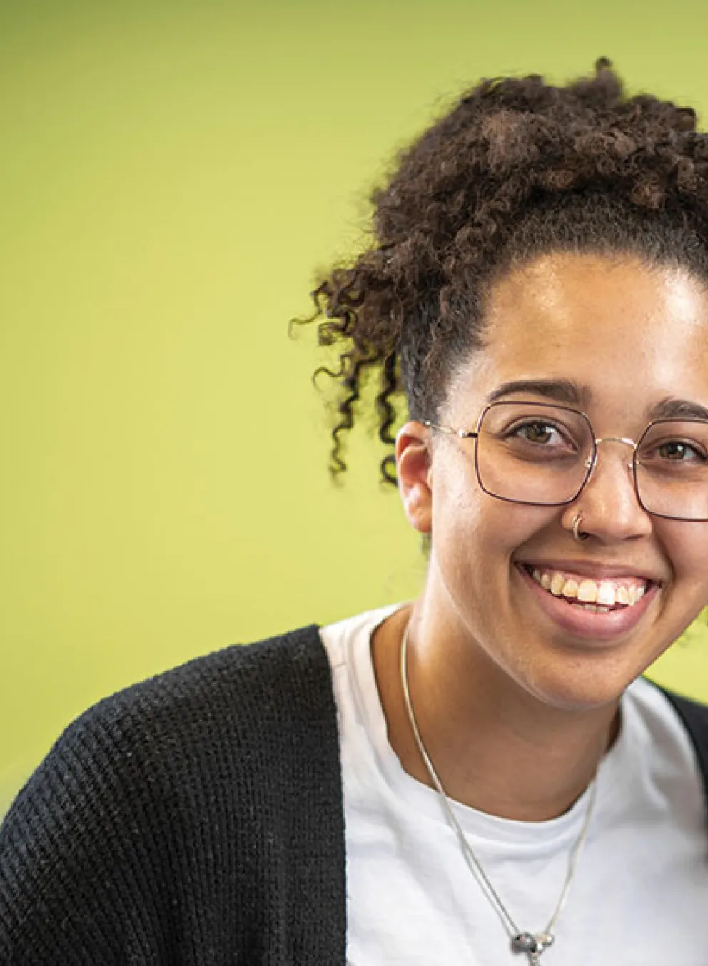 Two smiling women wearing glasses, posing together against a green background.