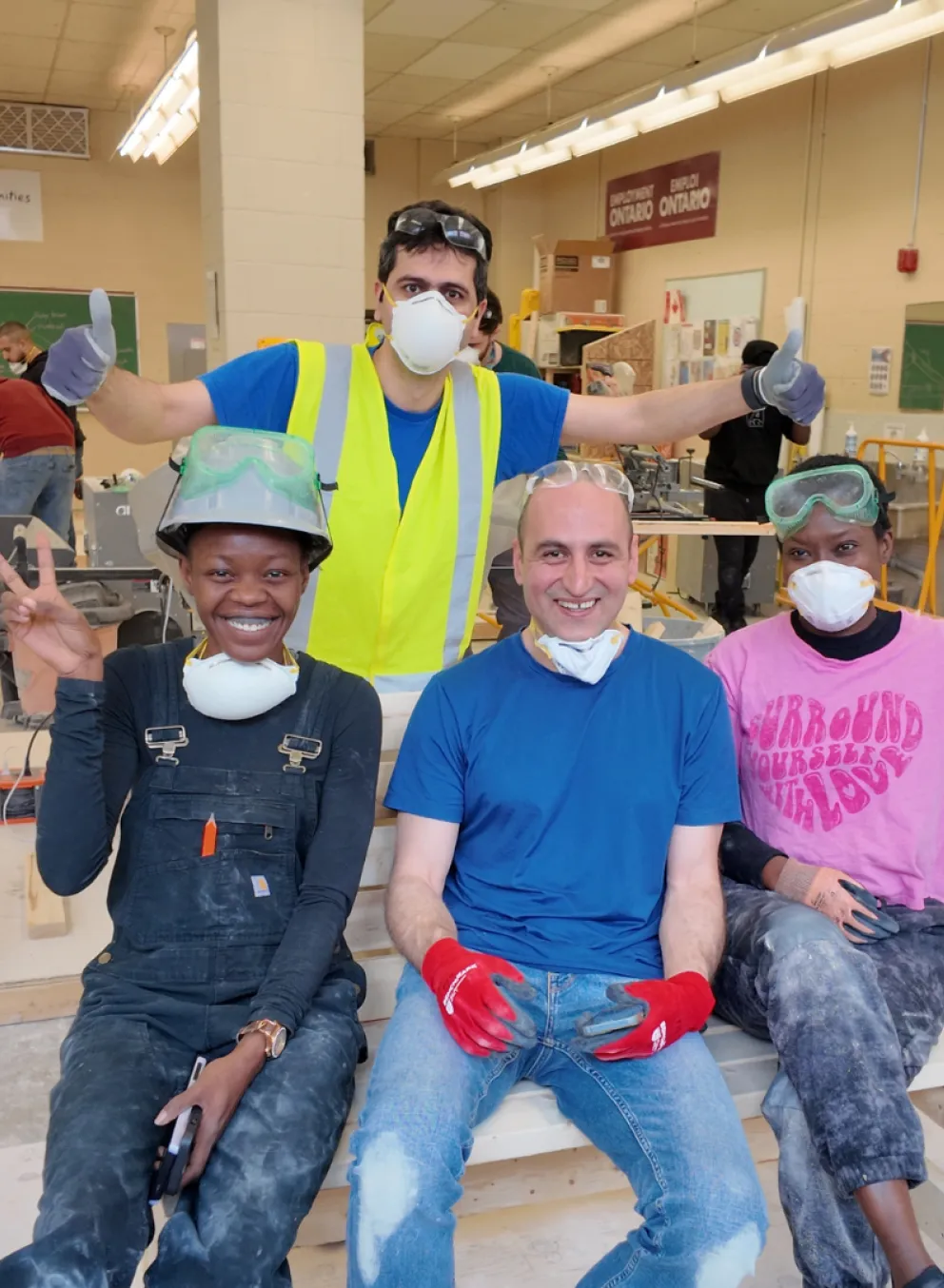 Four people posing for a group photo in a construction training workshop