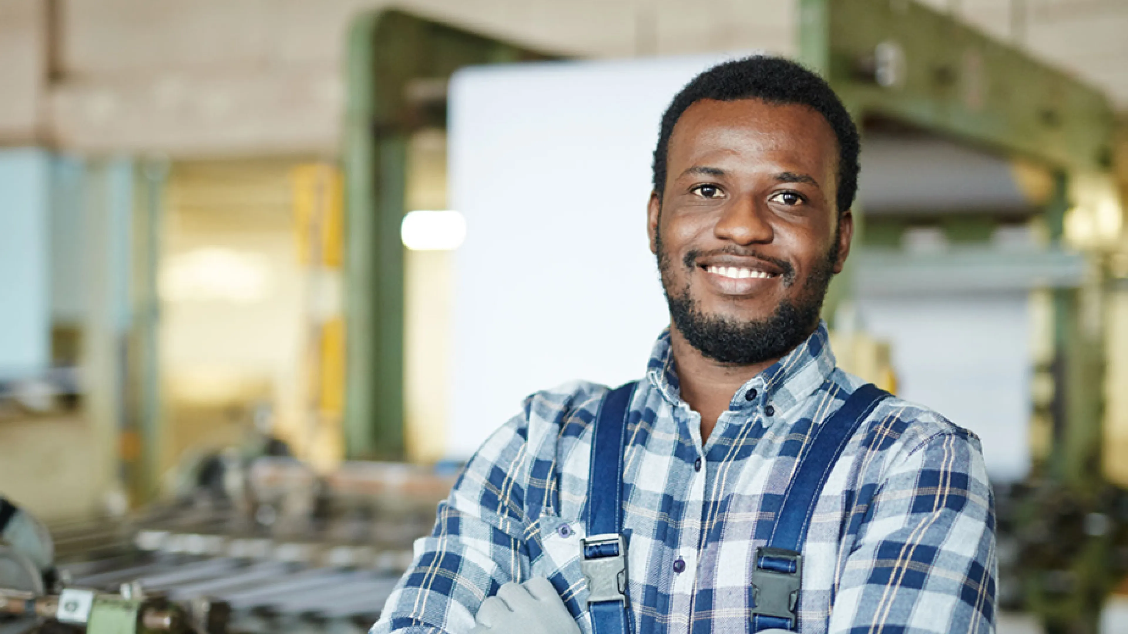 A smiling man with his arms crossed stands in front of machinery.