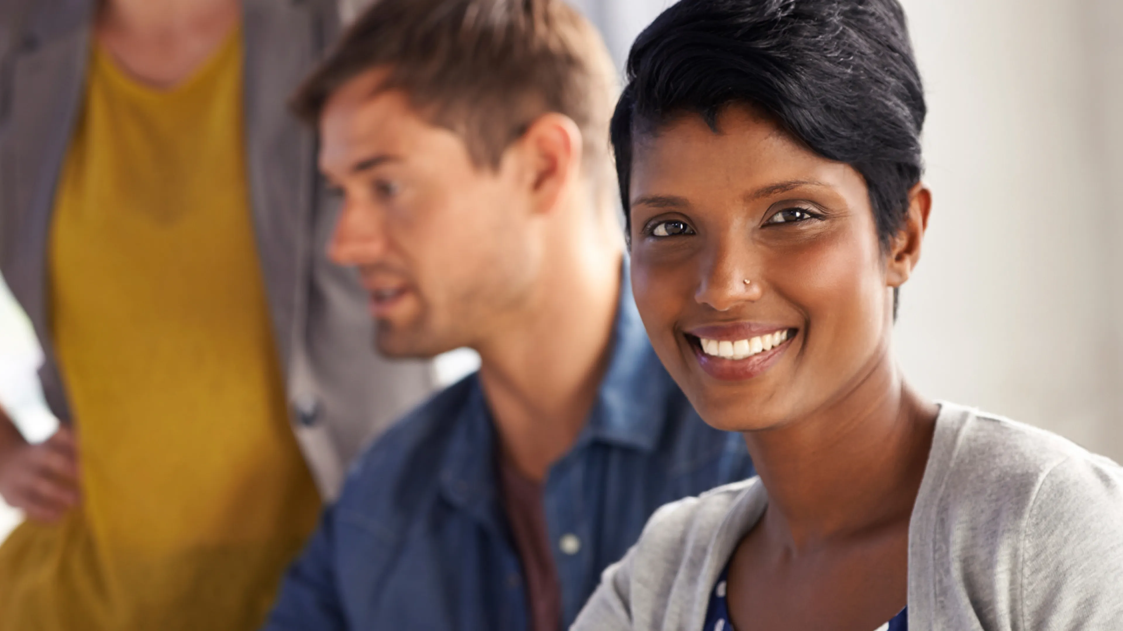 A smiling woman looks directly into the camera.