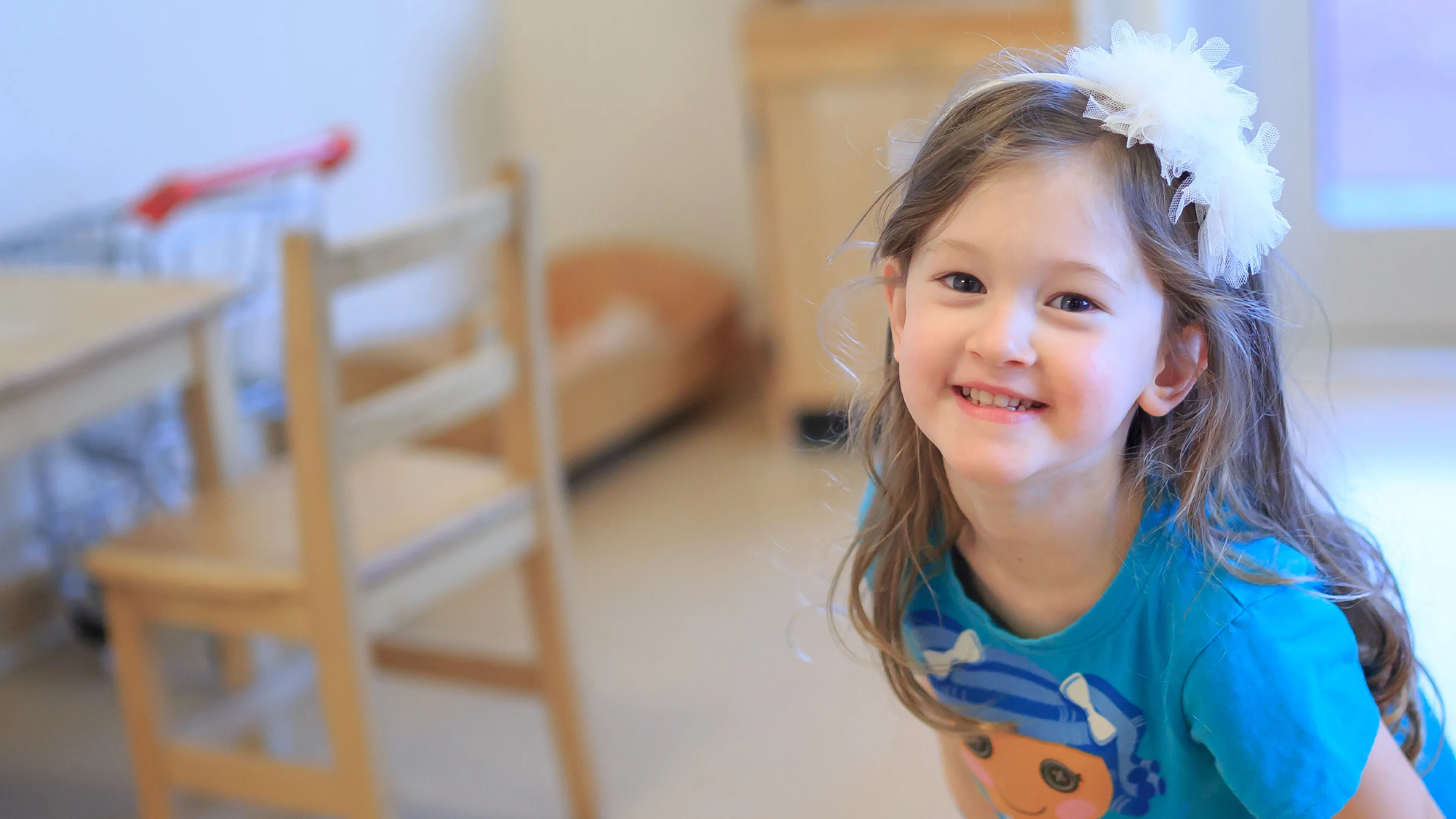 A smiling girl with a bow in her hair.