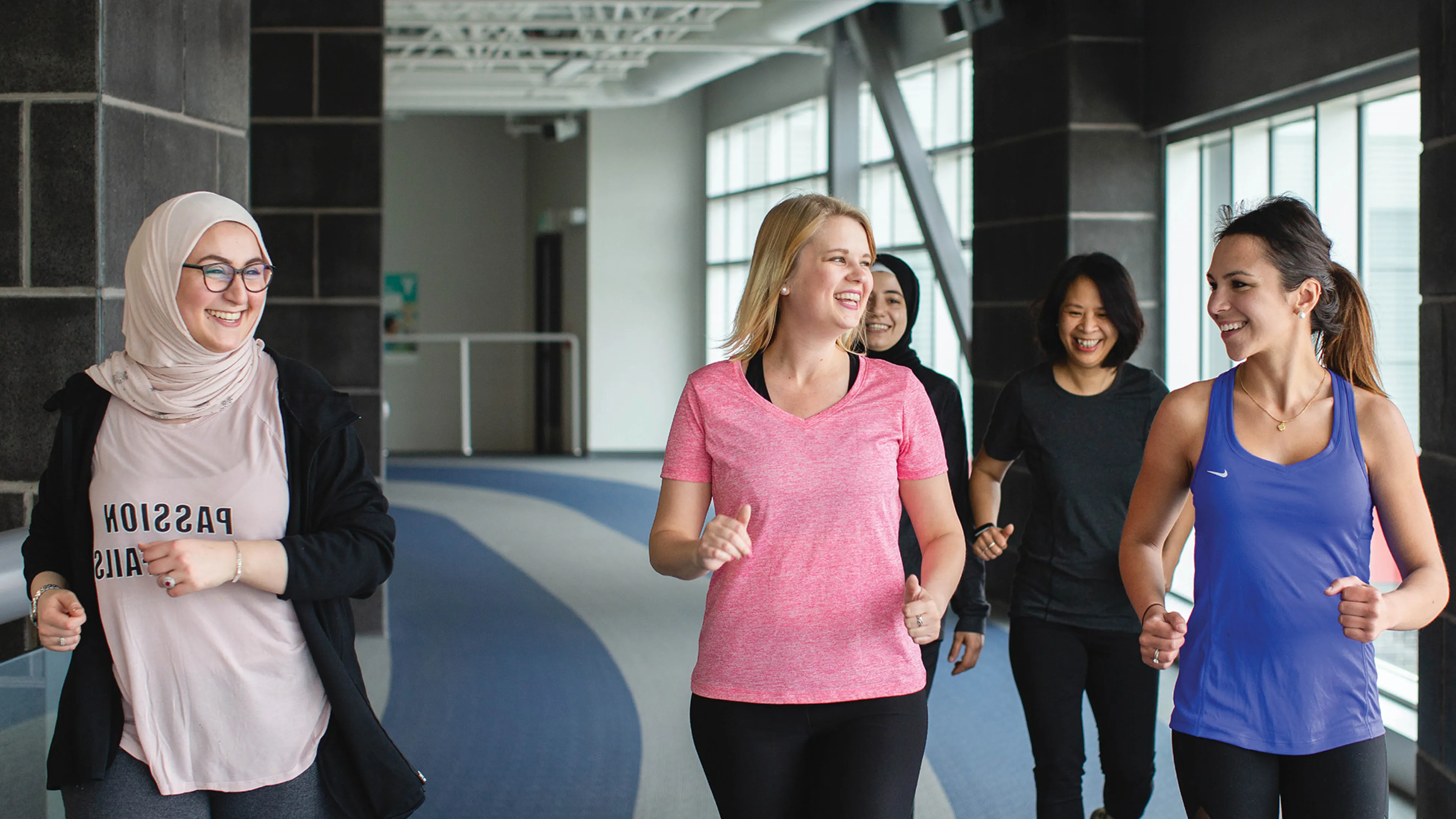 A group of friends walk together on an indoor track.