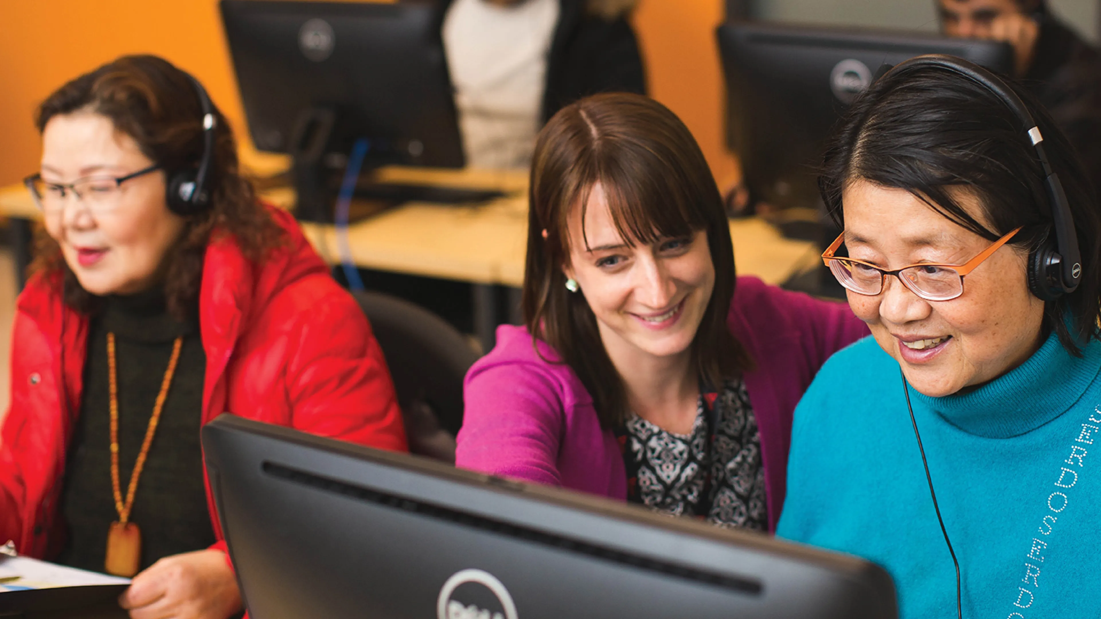 Three women sit at a classroom table.