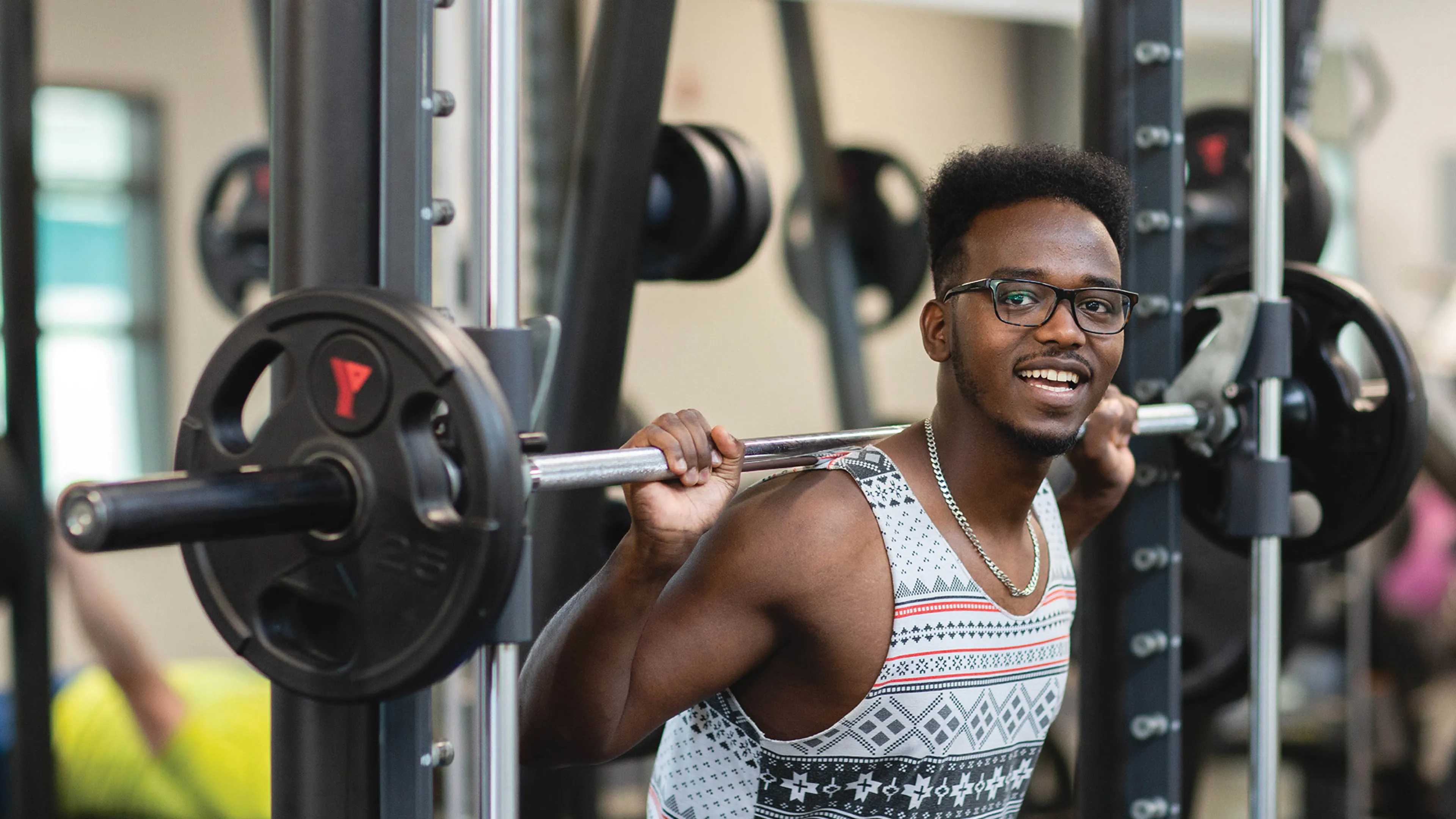 A young man holding up a barbell over his shoulder