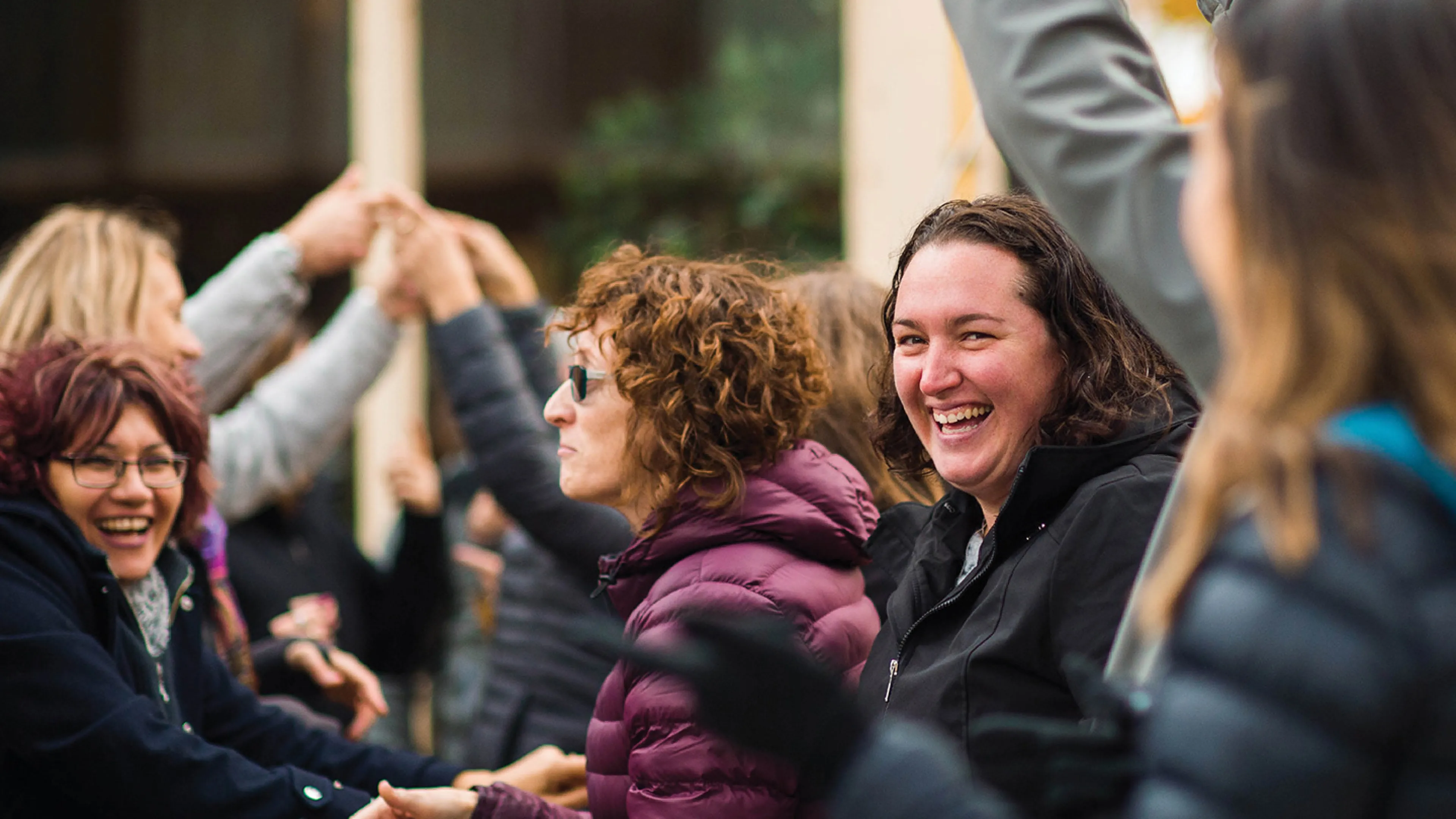 A group of adults participate in a team building exercise in an outdoor setting.