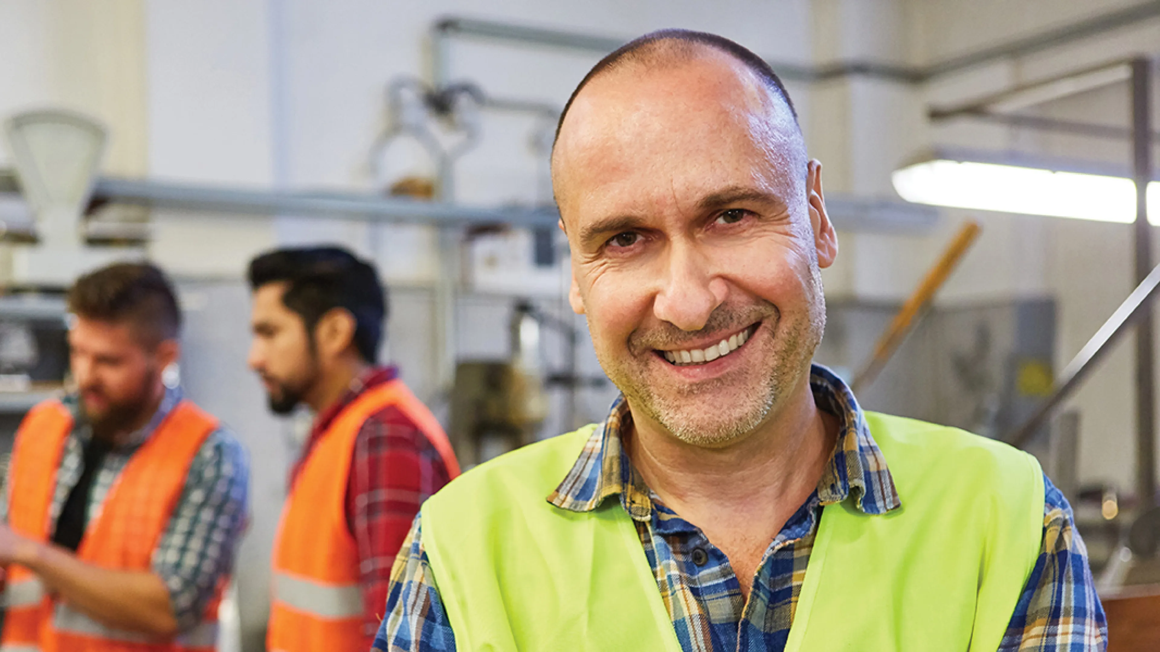 Three men working with safety vests on.