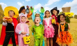 Eight children in various Halloween costumes posing in a field