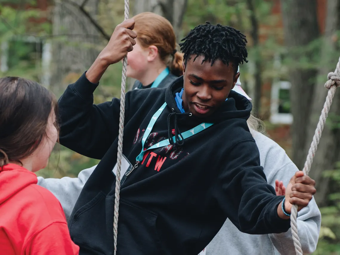 A team of people enthusiastically participating in a rope game, showcasing teamwork and fun in an open area.