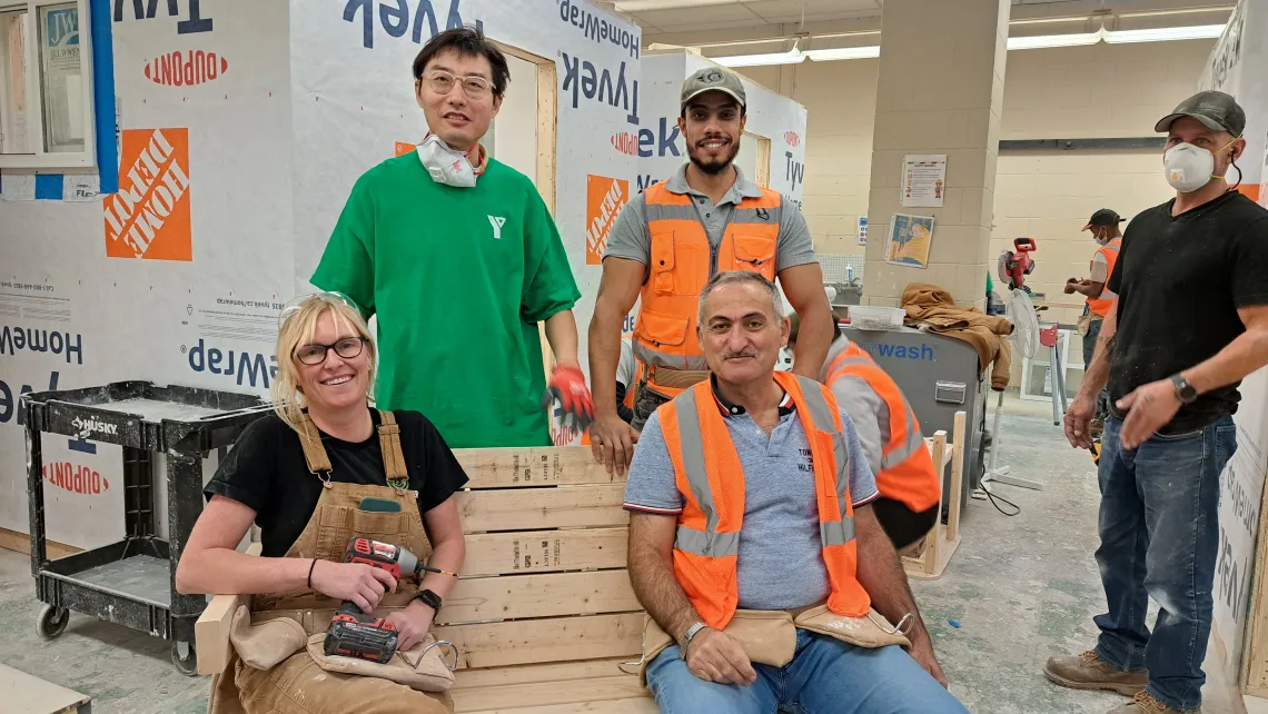 Four people wearing PPE in a construction workshop