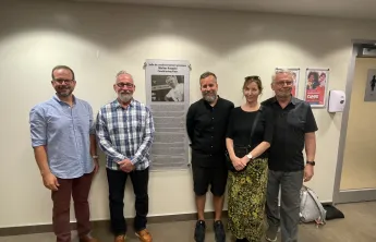 Five folks standing by "Walter Krepski Conditioning Floor" plaque