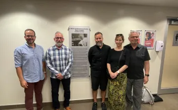 Five folks standing by "Walter Krepski Conditioning Floor" plaque